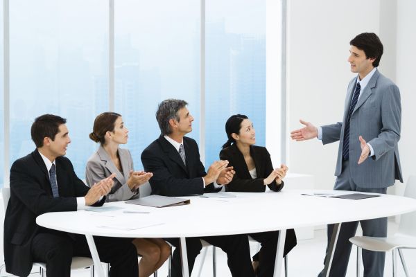 Business people applauding associate's presentation, sitting around table