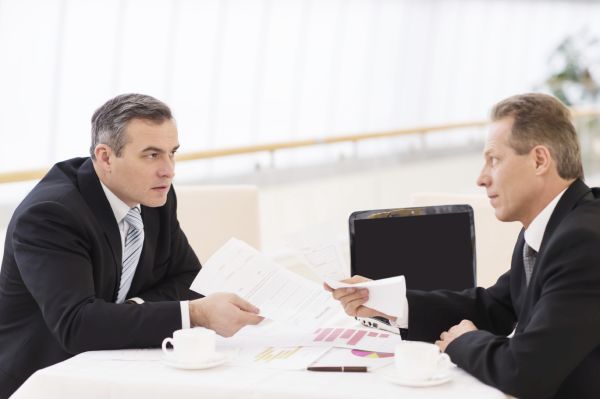 Business confrontation. Two mature men in formalwear arguing while sitting together at the table