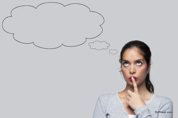 Woman with big brown eyes looking upwards thinking with blank thought bubbles above her head, isolated on white background.