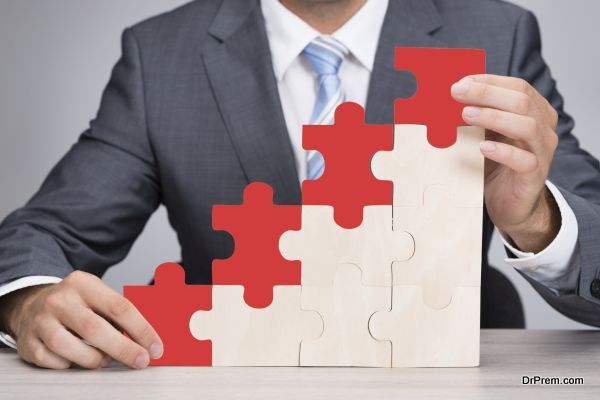 Midsection of businessman holding red jigsaw graph on table against gray background