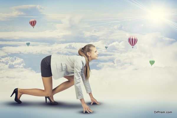 Businesswoman standing in running start pose, looking at light shining ahead. Sky with clouds and air balloons as backdrop