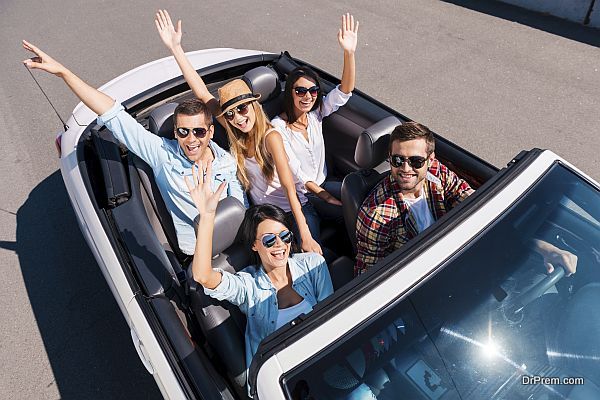 Traveling with fun. Top view of young happy people enjoying road trip in their white convertible and raising their arms