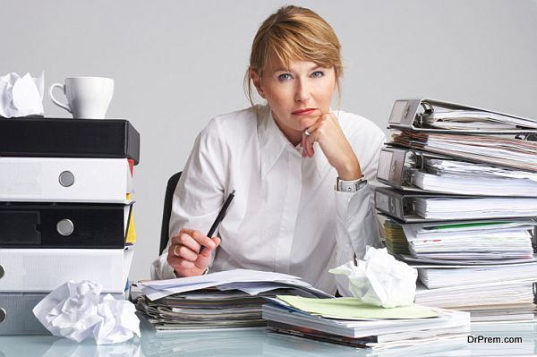 tired businesswoman is sitting at a table full of paperwork