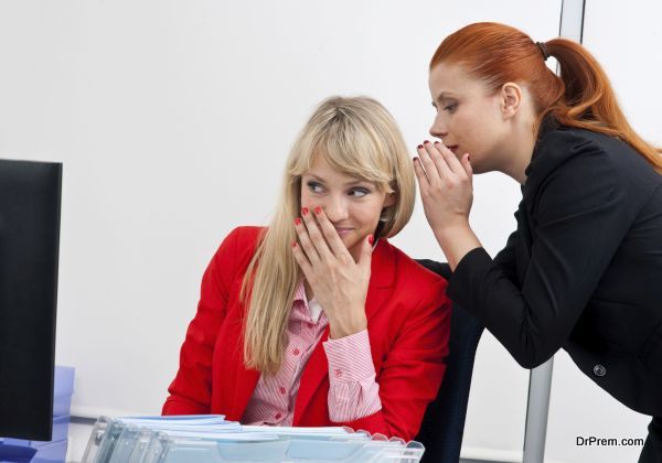 Two attractive business woman colegues gossip in office