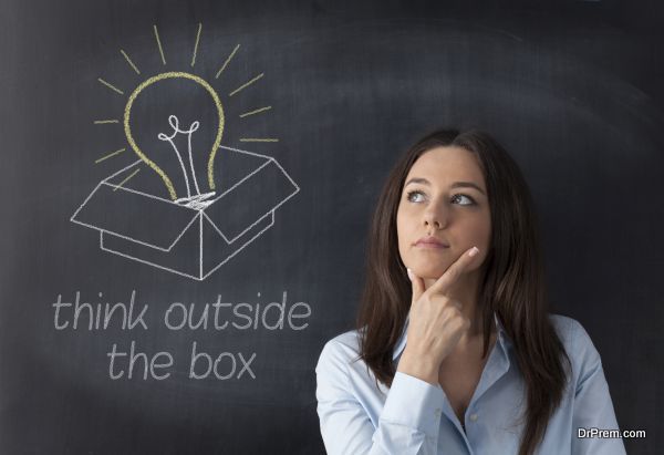 Businesswoman standing in front of chalkboard with light bulb and box drawn above her head. Concept about ideas