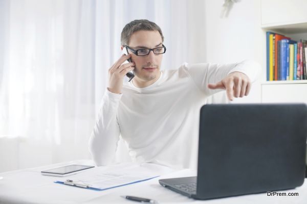 Young businessman working at home using laptop and mobile phone