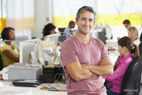 Portrait Of Man Standing In Busy Creative Office