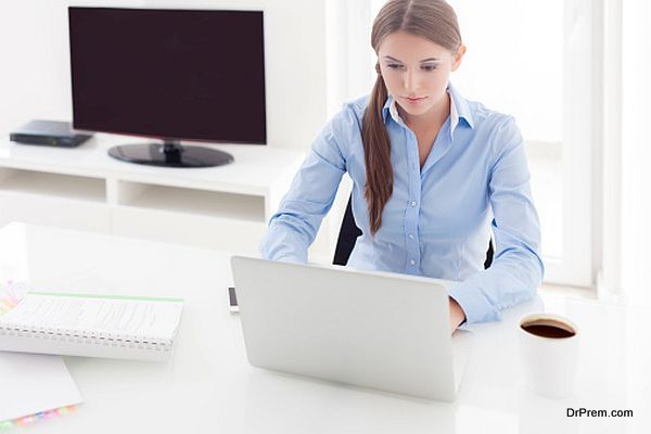 Businesswoman working on her laptop in front of television