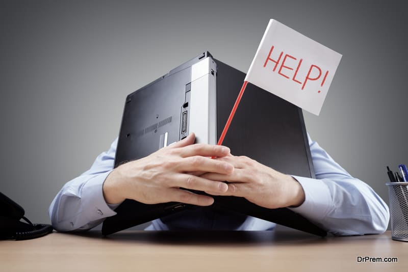 businessman burying his head uner a laptop computer asking for help