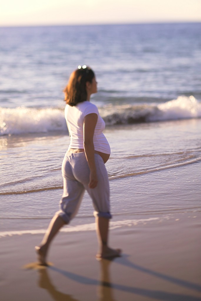 Pregnant woman walking on beach