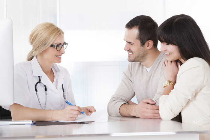 Happy Doctor Discussing With Couple