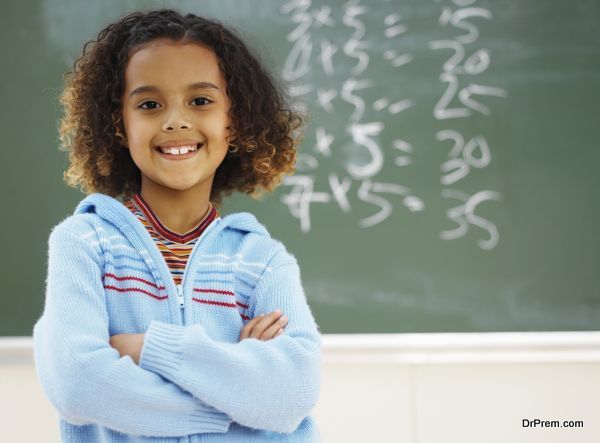 Front view portrait of girl standing in front of chalkboard with arms crossed (8-9)