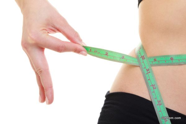 Weight loss. Green measuring tape on woman body