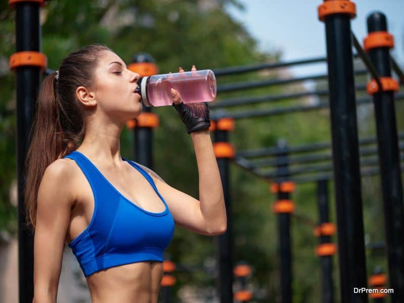 Sportive woman drinking vitamin water at the street gym