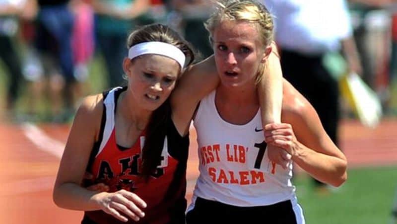 A runner helps a fallen competitor cross finish line