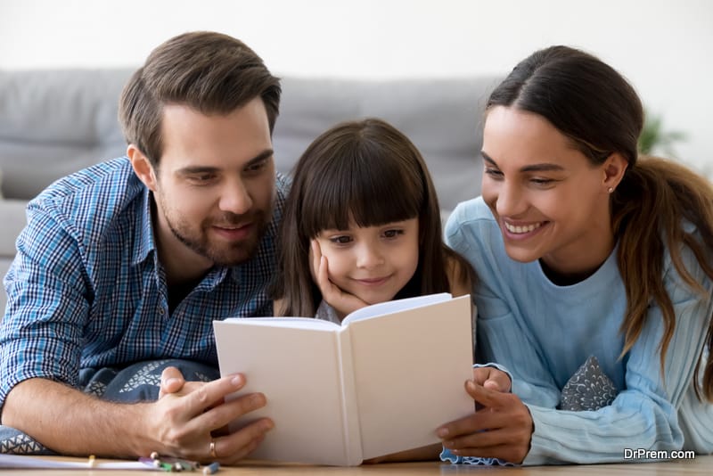 Happy-mom-and-dad-with-little-cute-daughter-holding-reading-book