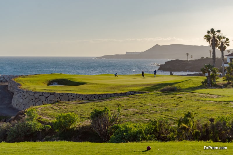 Golf players on a green facing the Atlantic Ocean on the island of Tenerife in Spain