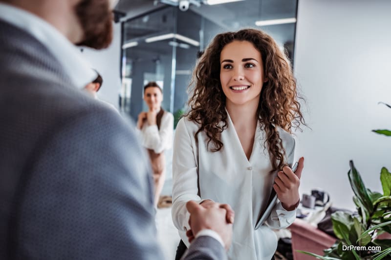 smiling beautiful young woman shaking hand to stylish man 