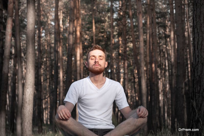 Young male person meditating in the forest