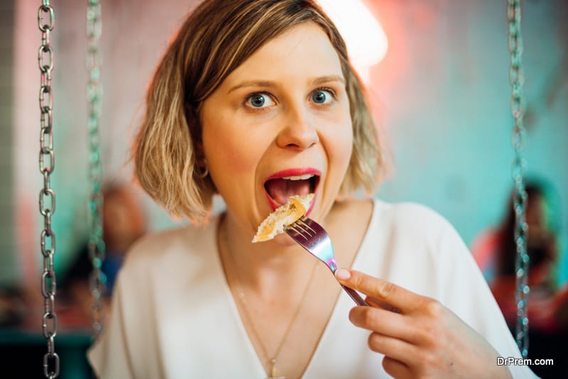 Funny young woman eating  in restaurant