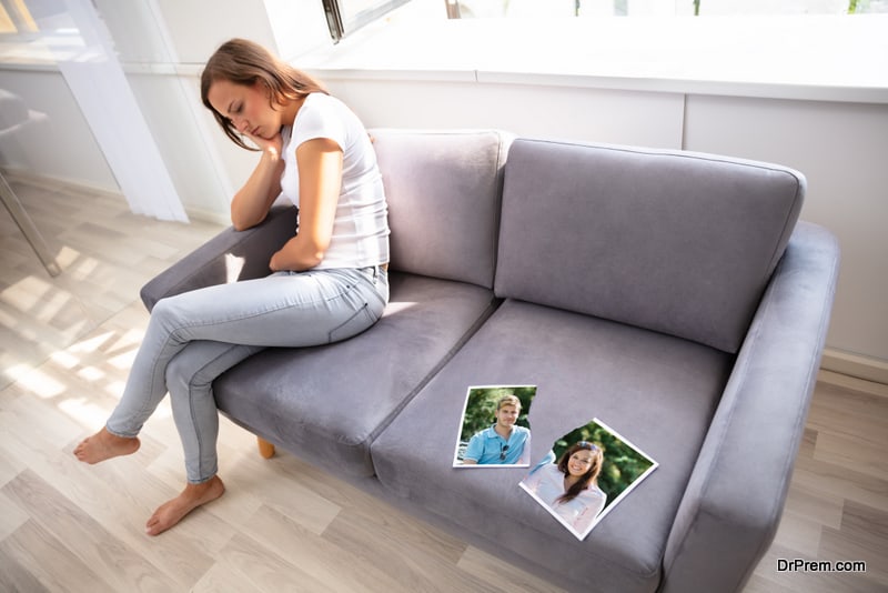 Lonely Woman Sitting On Sofa With Torn Photograph