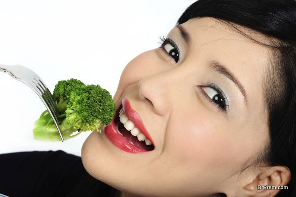 Young asian girl eating broccoli