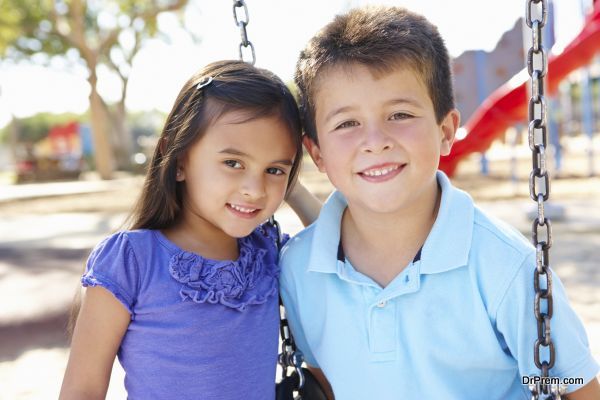 Boy And Girl Playing On Swing In Park