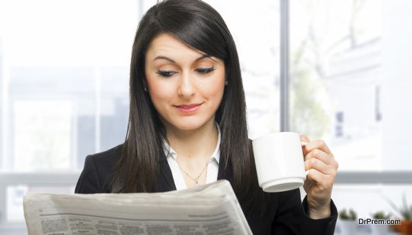 Beautiful woman reading the newspaper while drinking coffee