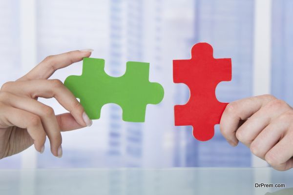 Cropped image of business people joining jigsaw pieces in office