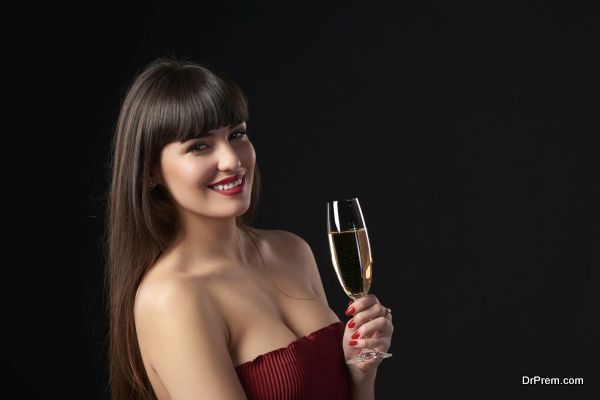 Sensual smiling woman holding a glass with champagne. Closeup portrait with copy space