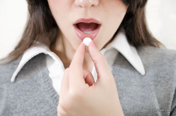 Close-up of young woman putting pill in mouth