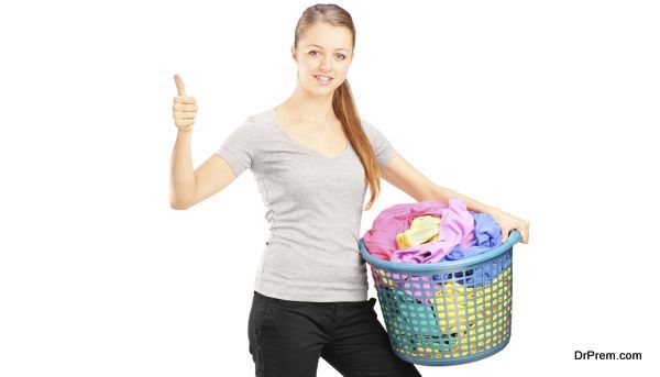 Young woman with basket full of clothes giving thumb up