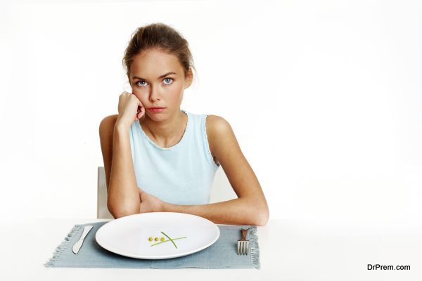 Portrait of sad girl looking at camera with peas and leeks on plate in front