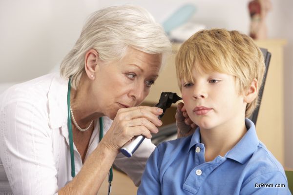 British GP examining young boy's ear