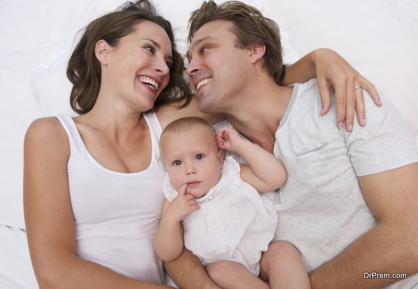 Portrait of a loving family holding cute baby in bed