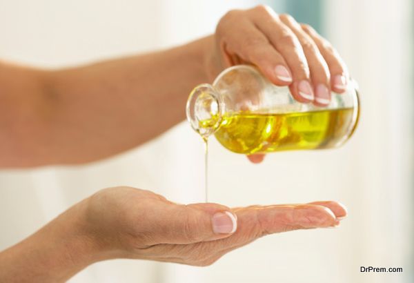 Woman pouring oil from bottle onto palm