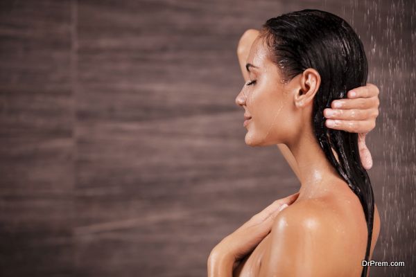 Enjoying a shower. Side view of beautiful young shirtless woman