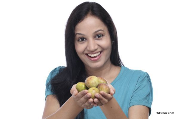 Young woman holding fig fruit in her hands against white background