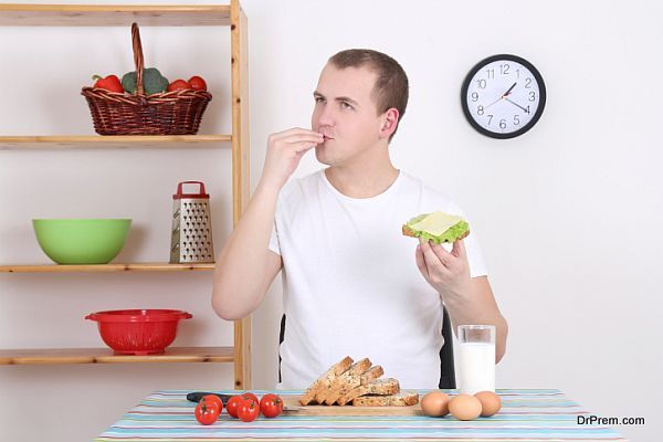 young man eating tasty sandwich in the kitchen