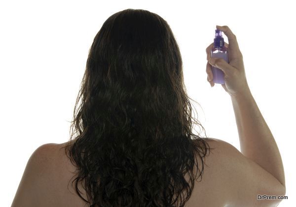 Woman spraying hair with styling product..