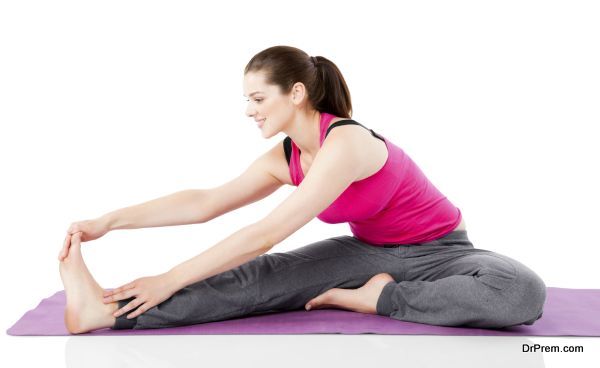 Happy young woman stretching legs on exercise mat over white background