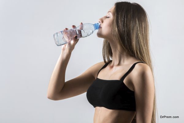 Slender sporty girl drinking water, resting after fitness exercises, tired, copy space