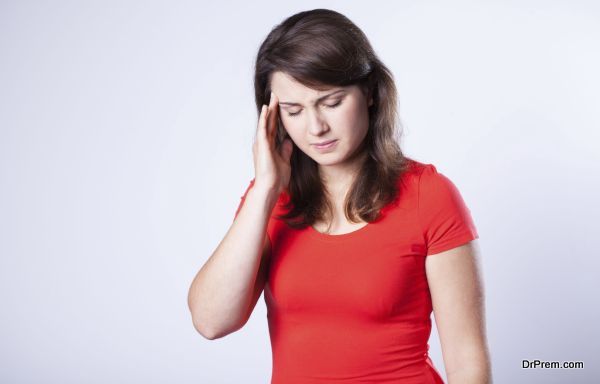 Young woman with headache on grey background