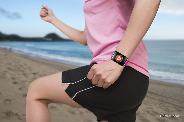 sport female wearing bright pink watchband bent touchscreen smartwatch with red health icon on natural sea beach background