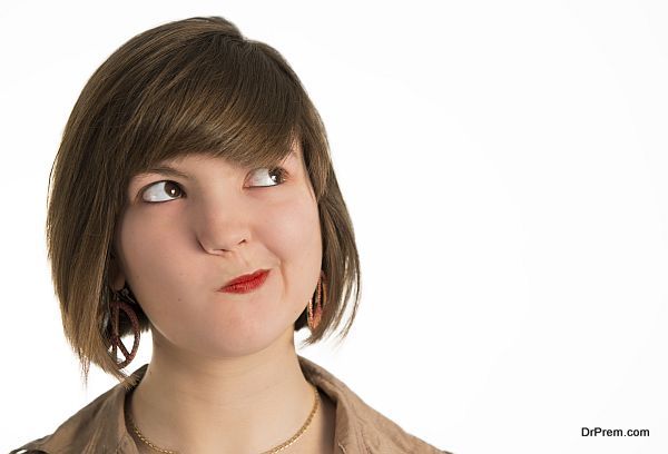 A young woman making a funny face while she is thinking.