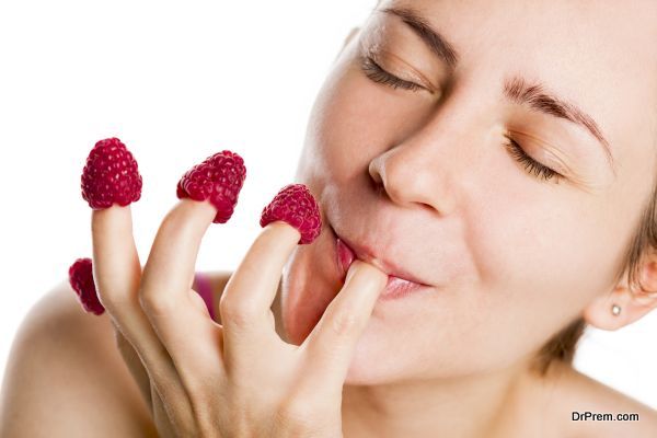 Young woman eating raspberries from fingers.