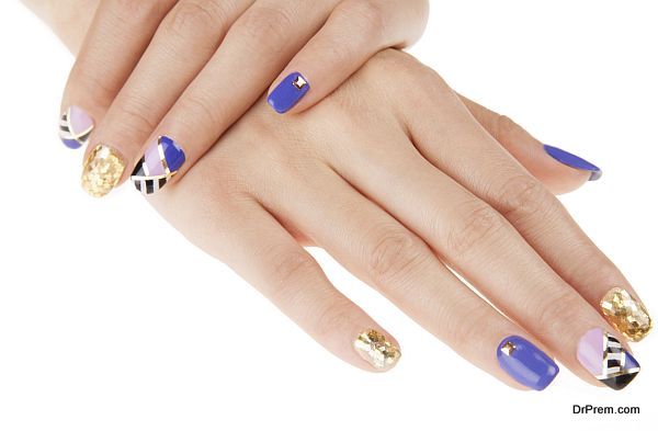 Nail art with gold colors and studs. Stylish geometric pattern.