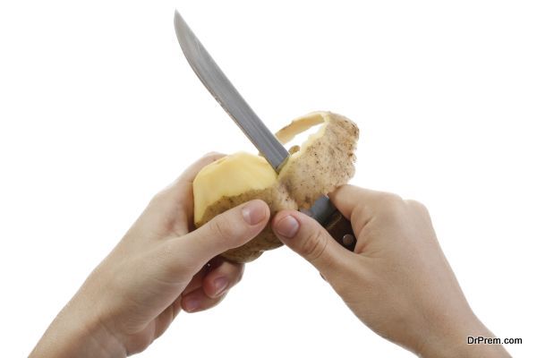Hand holding knife peeling potato vegetable food