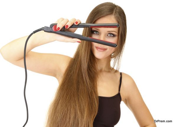 Woman doing hairstyle with hair straightener, isolated on white