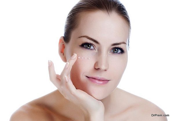 Beautiful sexy woman applying cosmetic cream on skin near eyes